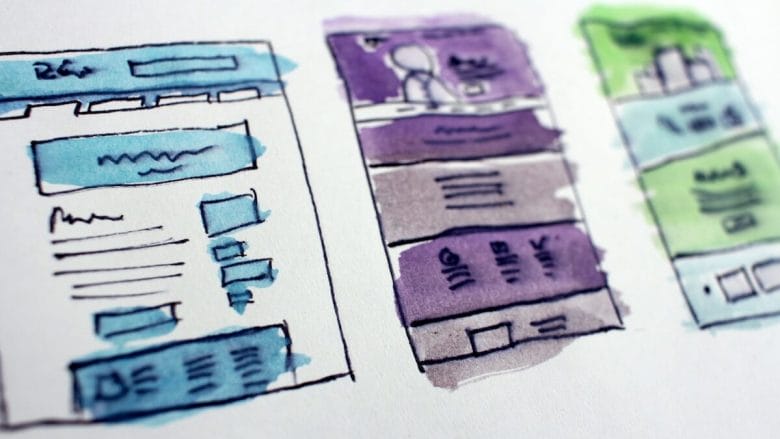 Three hand-drawn website wireframes with blue, purple, and green watercolor highlights on white paper.