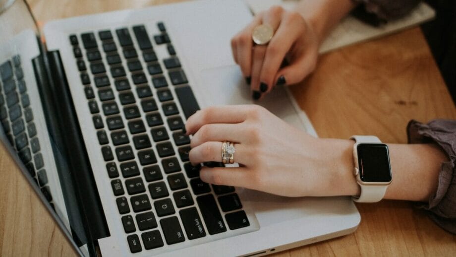 A woman typing on a laptop with an apple watch.