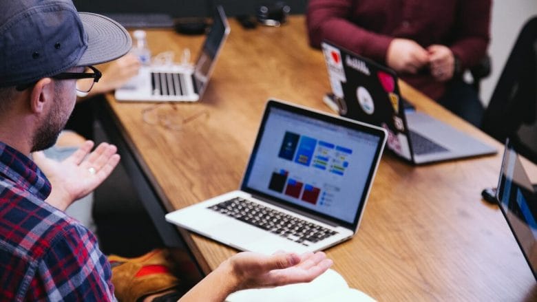 A group of people sitting around a table with laptops.