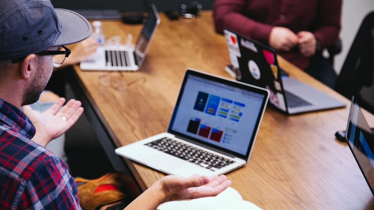 A group of people sitting around a table with laptops.