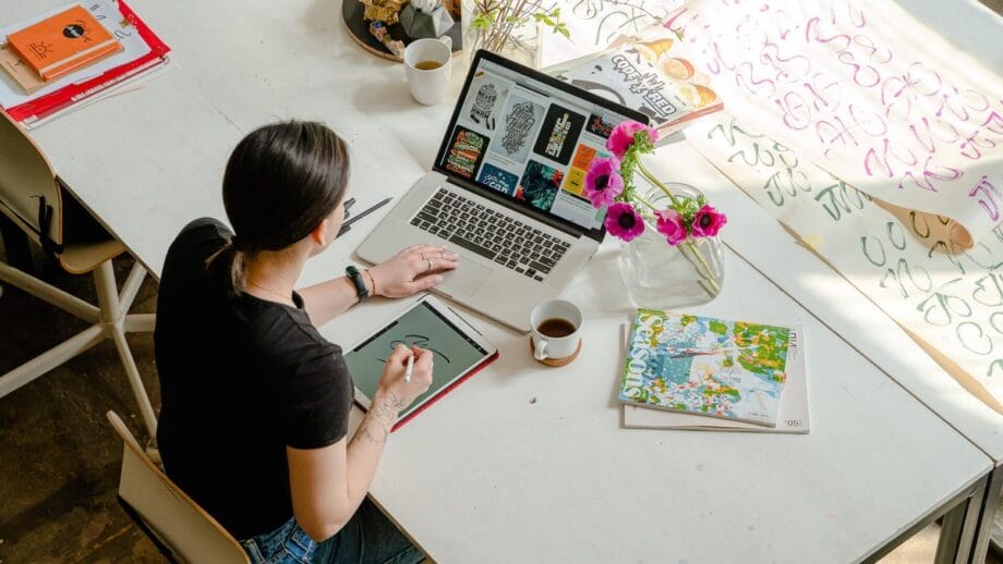 A woman working at a desk with a macbook laptop.