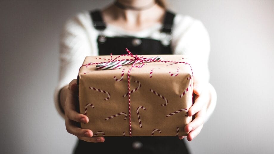 A woman holding a gift wrapped in brown paper.