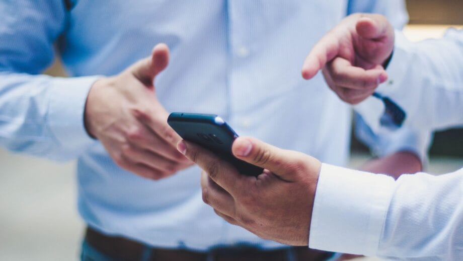 Two men are looking at a cell phone.