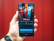 A person holding up a phone with disney channel on it.