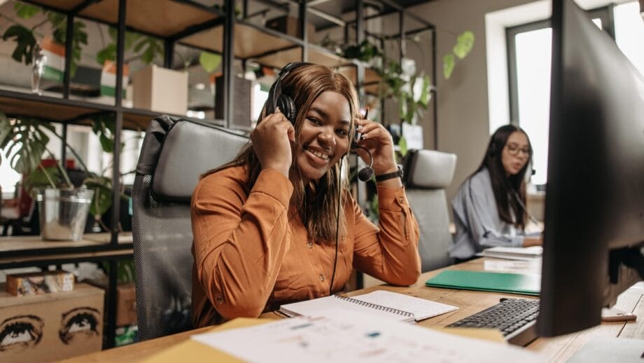 A woman wearing headphones at a desk in an office.