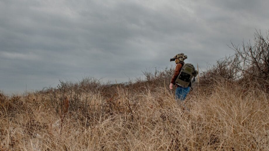 A man in a hat is standing in a field of tall grass.