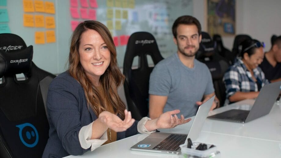 A group of people sitting at a desk with laptops in front of them.