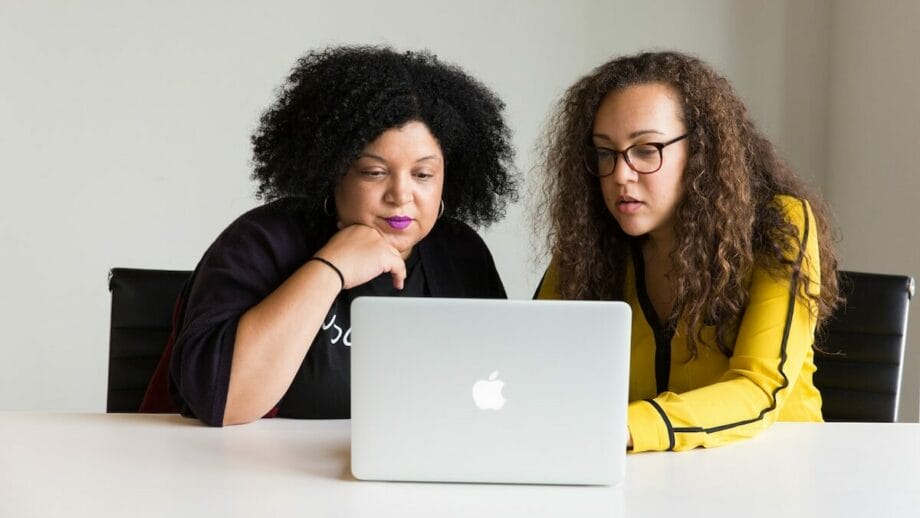 two women looking at the screen of a MacBook