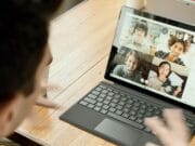 A man is sitting at a table with a laptop in front of him.