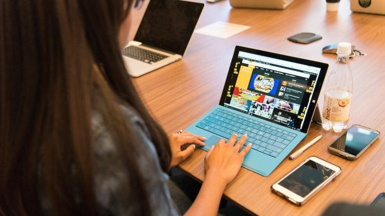 A woman sitting at a desk with a laptop and cell phone.