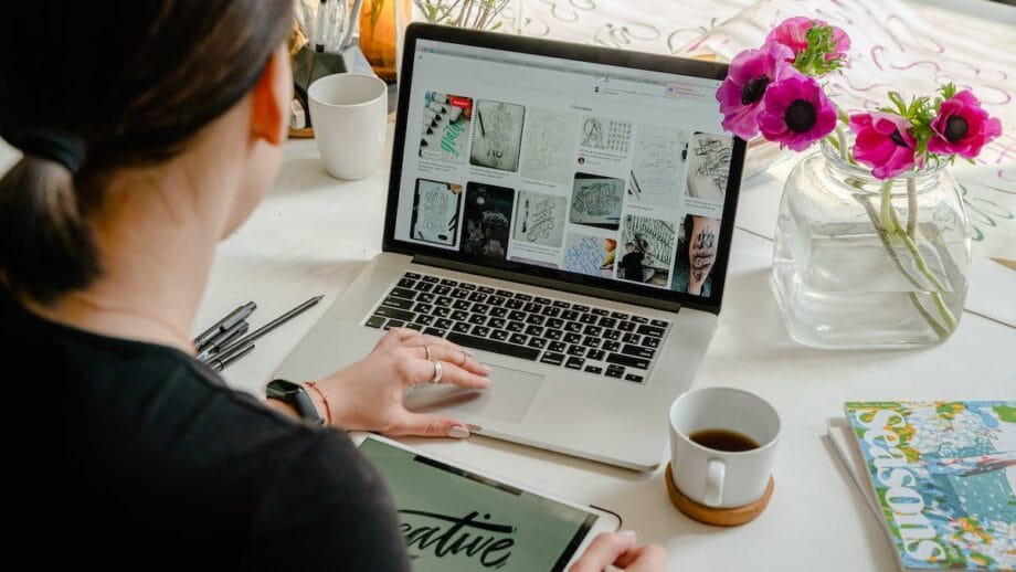 A graphic designer working on a laptop at a desk with flowers.