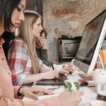 Three people working on a computer in an office.