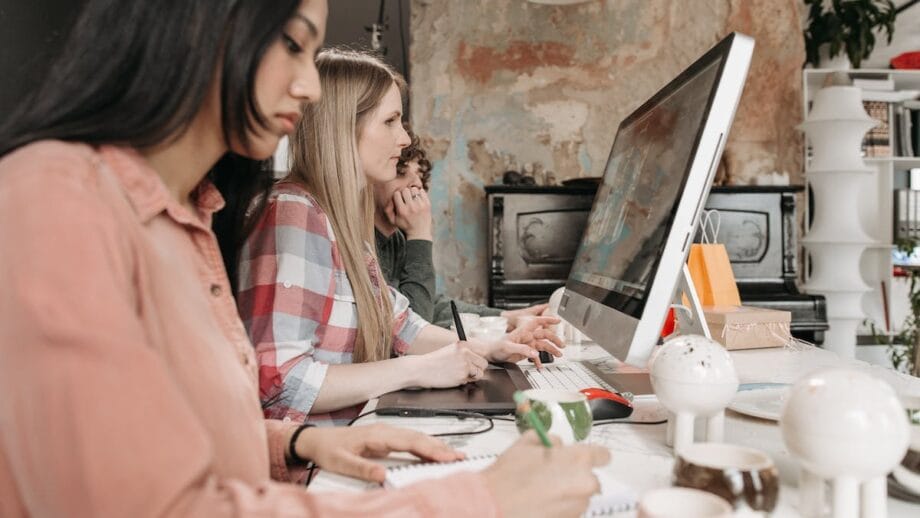 Three people working on a computer in an office.