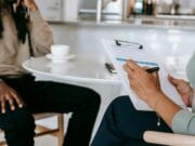 A man sitting at a table with a clipboard in front of him.