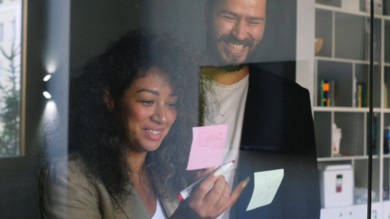 A man and a woman standing in front of a glass door.