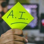 A man holding up a piece of paper with the word ai written on it.