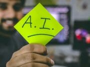 A man holding up a piece of paper with the word ai written on it.