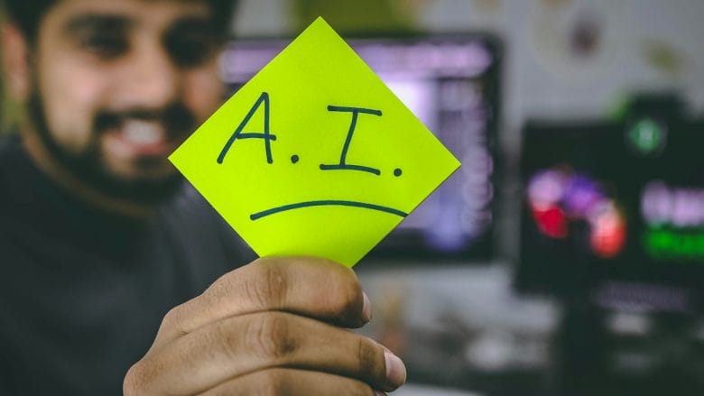 A man holding up a piece of paper with the word ai written on it.
