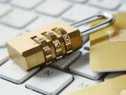 A gold padlock and credit cards sitting on top of a keyboard.