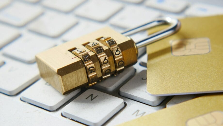 A gold padlock and credit cards sitting on top of a keyboard.