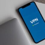 A phone with the word vpn on it sitting next to a laptop.