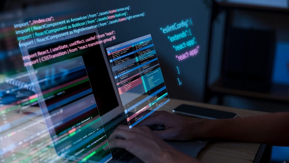 A person working on a laptop with code on the screen.