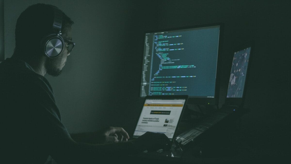 A man sitting in front of a computer screen in the dark.