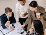 A group of businesspeople sitting around a table looking at performance graphs.