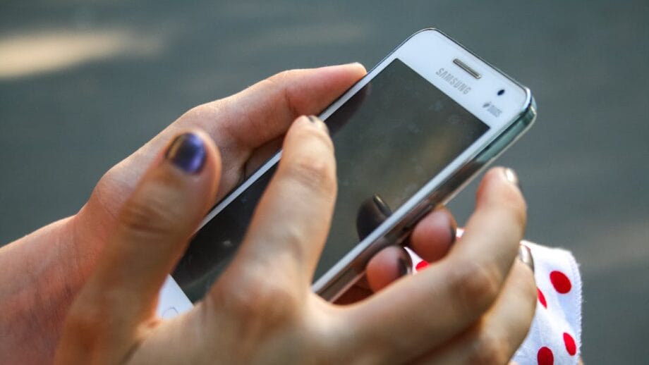 A person holding and operating a samsung smartphone with their right hand.