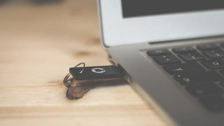 Usb flash drive connected to a laptop on a wooden desk.