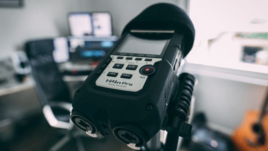 A portable audio recorder mounted on a tripod in a home studio setting.