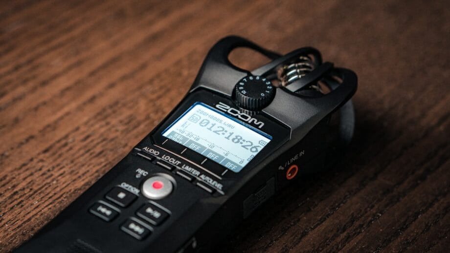 A portable audio recorder on a wooden surface displaying a digital readout.