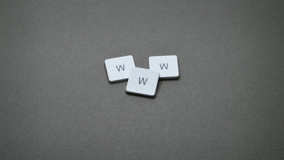 Three white keyboard keys with the letter "W" are arranged on a dark gray surface.