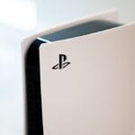 A close-up of a PlayStation 5 console with a white exterior and black interior, displaying the PlayStation logo on its side.