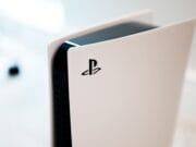 A close-up of a PlayStation 5 console with a white exterior and black interior, displaying the PlayStation logo on its side.