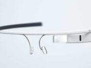 A close-up view of a pair of smart glasses with a lightweight, minimalist design, featuring a small rectangular display on one side, nose pads, and a thin frame.