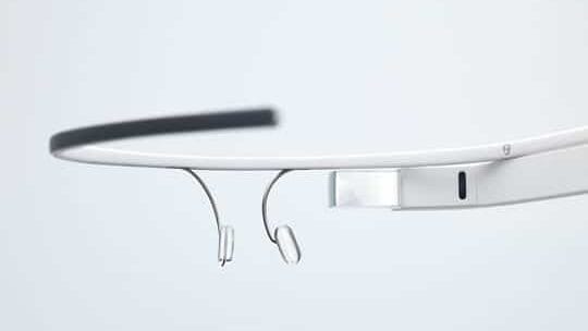 A close-up view of a pair of smart glasses with a lightweight, minimalist design, featuring a small rectangular display on one side, nose pads, and a thin frame.