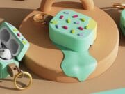 AirPods Pro case designed to look like a melting ice cream bar with colorful sprinkles and a keyring attachment, placed on a beige platform.