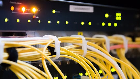 Close-up view of network cables connected to a server rack, with various status lights illuminated.