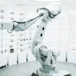 A sleek robotic arm in a well-lit, modern laboratory filled with organized rows of containers.