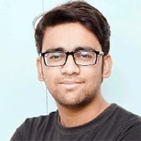 Maaz Amin, the author of this article, wearing glasses and a black shirt smiles at the camera against a light background.