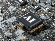 Close-up of a complex computer circuit board featuring a prominent central chip labeled "AI" surrounded by smaller components.