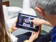 Dentist showing a patient dental X-rays on a tablet, pointing at specific areas.