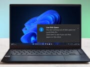 Laptop displaying a low disk space warning on Windows desktop.