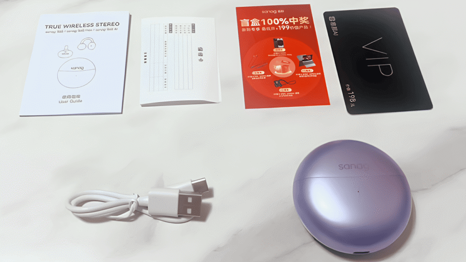 Contents include a purple Sanag S6S Open Ear Clip Earphone case, a USB charging cable, user guides, promotional pamphlets, and a VIP card, all spread out on a light surface.