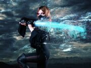 Person in a black outfit holds a glowing blue energy sword against a stormy sky backdrop.