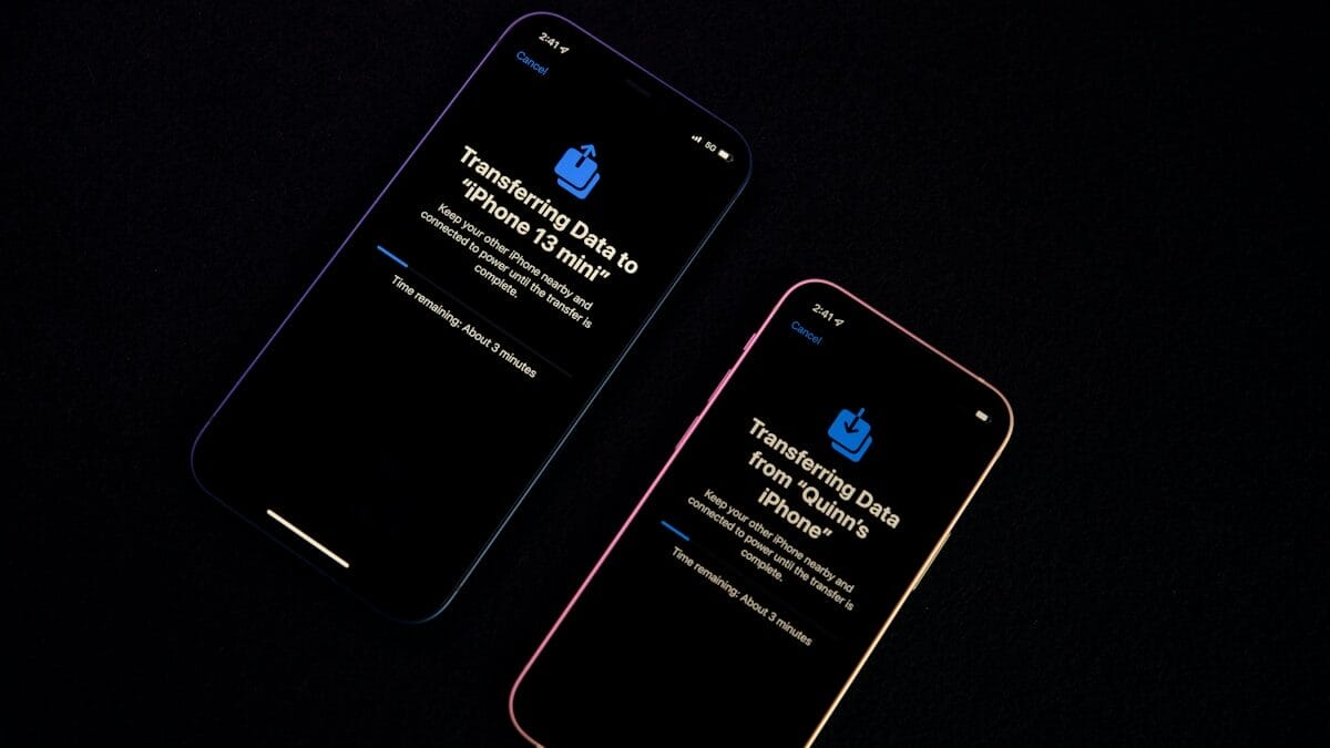 Two iPhones transferring data between each other, displaying a progress update on black screens.