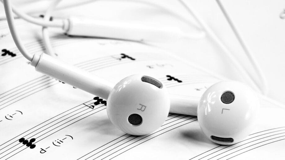 White earbuds resting on a sheet of musical notes.