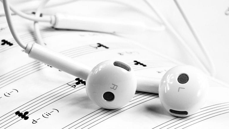 White earbuds resting on a sheet of musical notes.