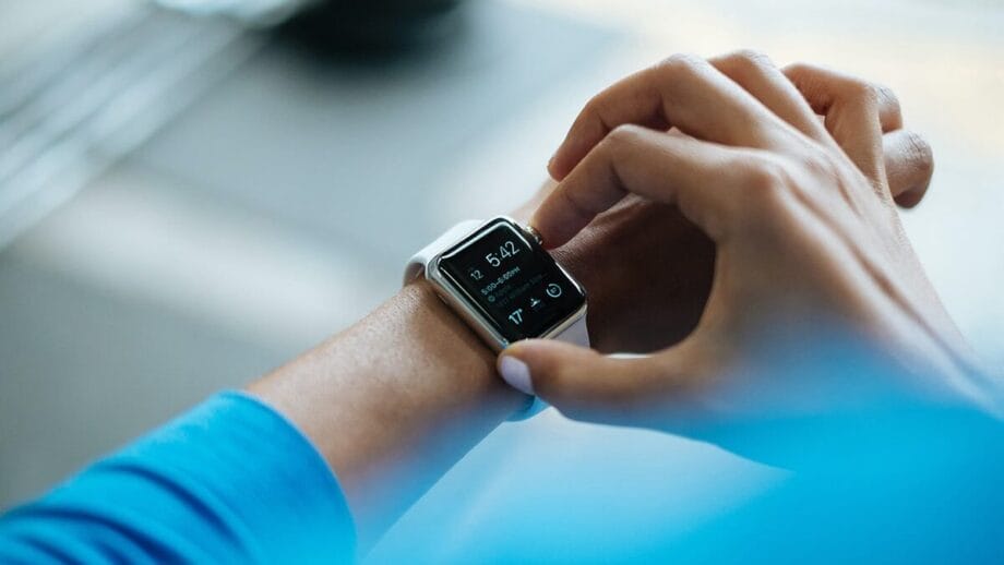 A person interacts with a smartwatch displaying the time, date, and notifications.